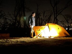 Man by tent at night