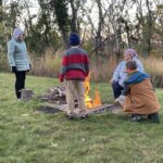 People stand around firepit