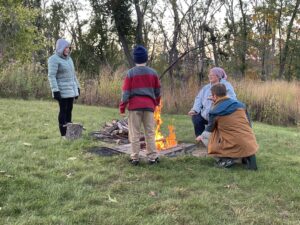 People stand around firepit