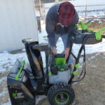 Man inserts lithium battery into EGO snowblower