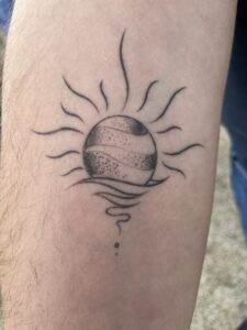 Arm with sun tattoo.