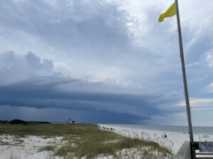 Shelf cloud and yellow warning flag on Gulf Shore beach.