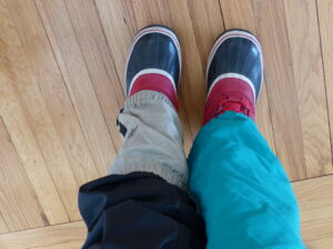 View of legs: Left wind pants and low gaiters over boots. Right long gaiters over boots.