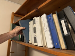 Man reaches for journals on shelf
