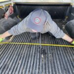 Boy measuring truck bed width.