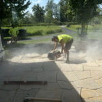 Man with hearing protection cuts pavers.