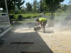 Man with hearing protection cuts pavers.