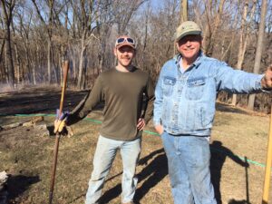 Two men in front of burned area after a successful burn.