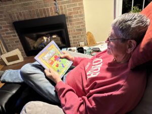 Man reading seed catalog by fireplace