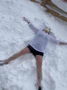 Woman making snow angel at a sauna on the UP of Michigan.